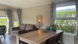 Una sala de estar moderna con una mesa de comedor de madera, un sofá y una lámpara de pie.
