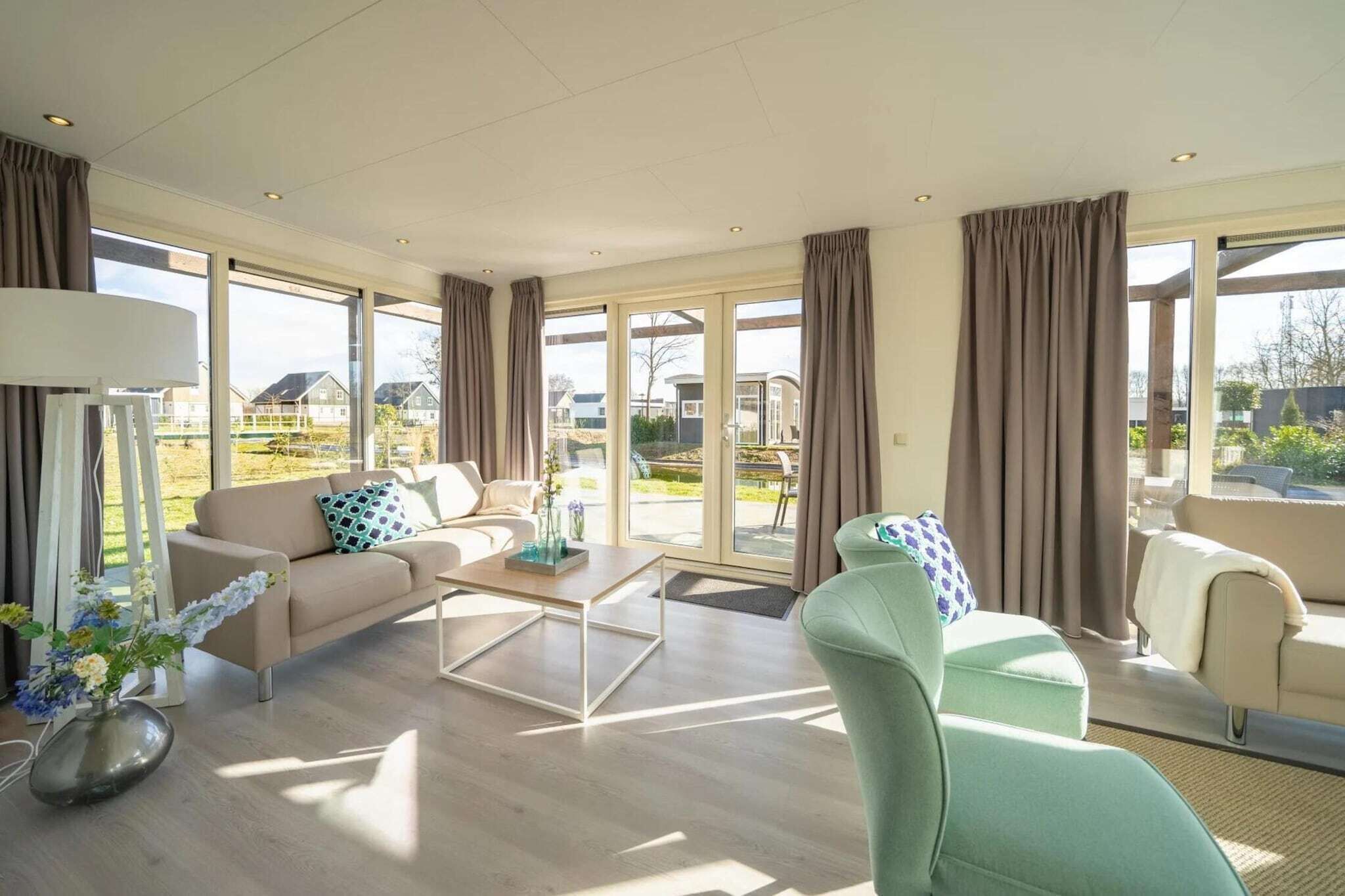 Een ruime woonkamer met een bank, fauteuil, salontafel en uitzicht op buiten.