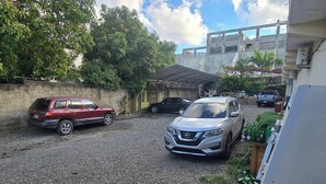 A gravel parking area with a red SUV and a silver Nissan SUV.