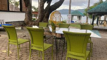 A table with chairs, a hanging chair, and a view of the sea.