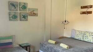Une chambre avec deux lits, une petite table et des œuvres d’art accrochées au mur.