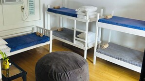 Une chambre avec des lits superposés, une petite table avec une plante et un climatiseur fixé au mur.