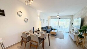 Ein modernes Wohnzimmer mit Essbereich, einer Couch, einem Couchtisch und einem Fernseher.