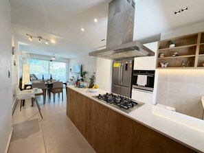 A modern kitchen with a central island, stainless steel appliances, and a dining area with a view. - Sky, sea, picuzzi and wind in the Caribbean (Punta Cana)