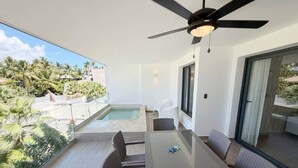 Ein Balkon mit Glastisch, Stühlen, Deckenventilator und Pool.