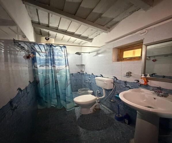 Une salle de bain avec des toilettes, un lavabo et un rideau de douche.