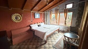 Un dormitorio con cama, sofá, una mesita y una ventana con cortinas.