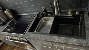 Una cocina moderna con un lavamanos de acero inoxidable, una estufa empotrada y una cafetera.