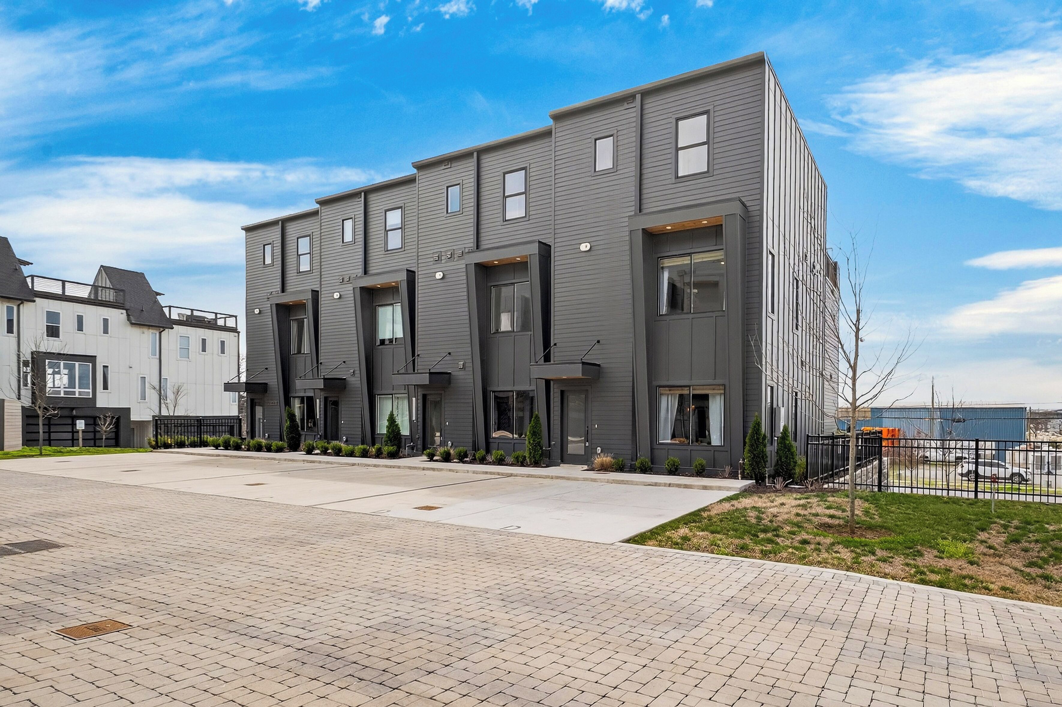 Un immeuble r ésidentiel moderne à plusieurs étages, doté d’un toit plat, de grandes fenêtres et d’une allée pavée.