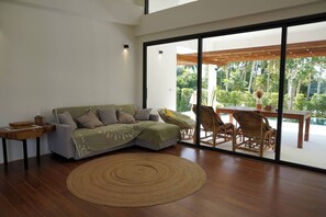 A modern living room with a sofa, a round woven rug, and wicker chairs. - O3 Green 2b Garden Pool Villa and Unique Furniture (Tambon Ko Pha-ngan)