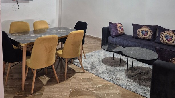 Een woonkamer met een eettafel, stoelen, een bank en een televisie.