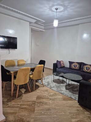 Un salon comprenant une table à manger, des chaises, un canapé et un téléviseur.