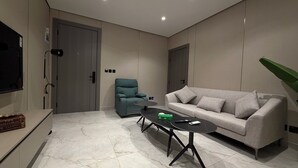 A modern living room with a sofa, a teal armchair, a coffee table, and a television. - 002 tara-JRE Jabal Al Lweibdeh with stunning view (Amman)