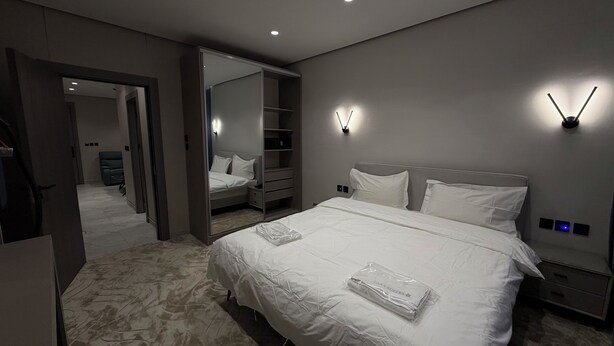 A modern hotel room with a large bed, a walk-in closet, and a bathroom visible through an open door. - 002 tara-JRE Jabal Al Lweibdeh with stunning view (Amman)