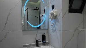 A bathroom with a marble sink, a mirror with a blue light, a hairdryer, and a trash bin. - 002 tara-JRE Jabal Al Lweibdeh with stunning view (Amman)