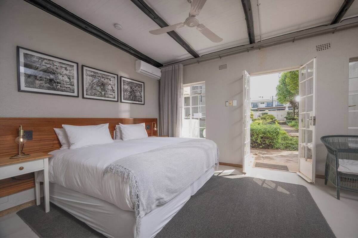 A bedroom with a bed, a desk, a chair, and a ceiling fan.