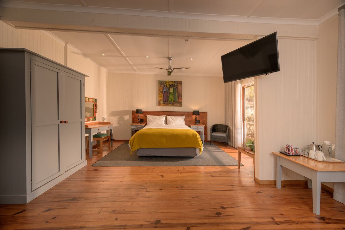 A bedroom with a bed, a television, a desk, a chair, and a wardrobe.