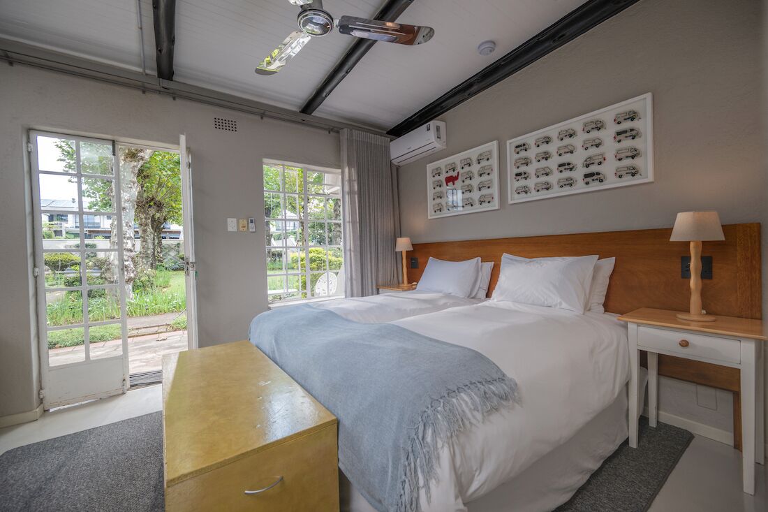 Une chambre d’hôtel avec un grand lit, une table de chevet, un bureau et une vue sur la verdure.