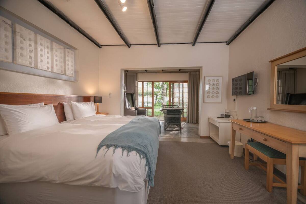 A hotel room with a large bed, a desk, a chair, and a TV.