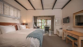 Quarto de hotel com uma cama grande, uma escrivaninha, uma cadeira e uma televisão.