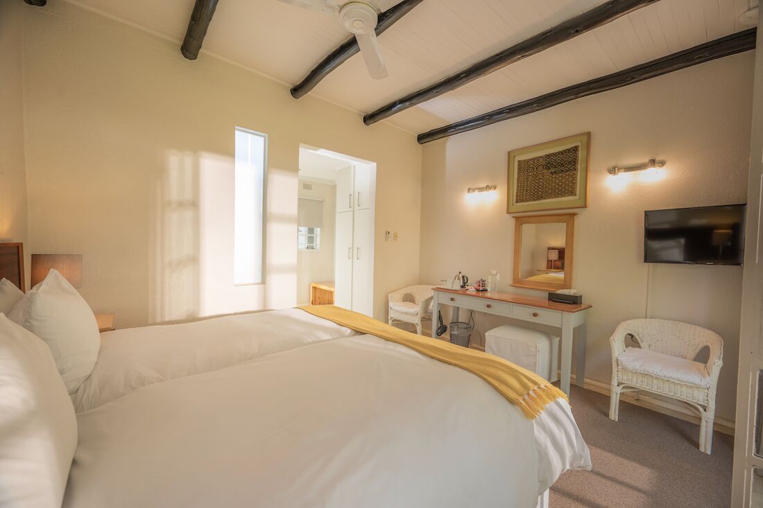 Un dormitorio con dos camas, un escritorio, una silla, un televisor y un ventilador de techo.