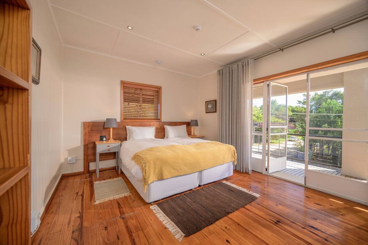 A bedroom with a bed, nightstands, a window, and a balcony.