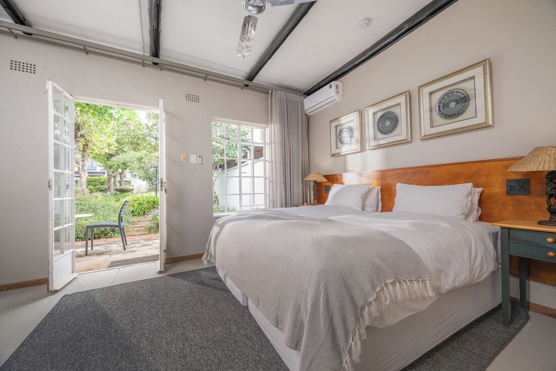 Une chambre à coucher avec un lit, une table de chevet, une lampe et une fenêtre.