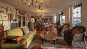 Un salon spacieux comprenant un canapé, des fauteuils, une table basse et un lustre.