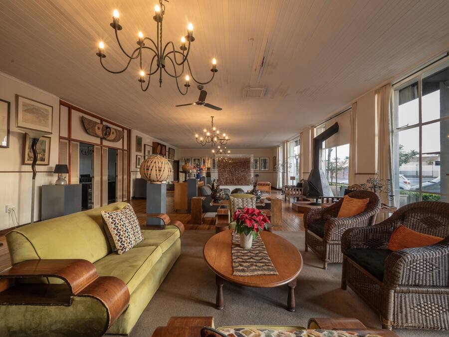 A spacious living room with a sofa, armchairs, a coffee table, and a chandelier.