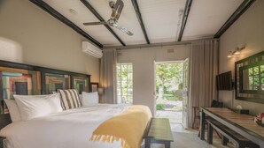 Une chambre à coucher comprenant un lit, un bureau, une chaise, un banc, un ventilateur de plafond et une vue sur l’extérieur.