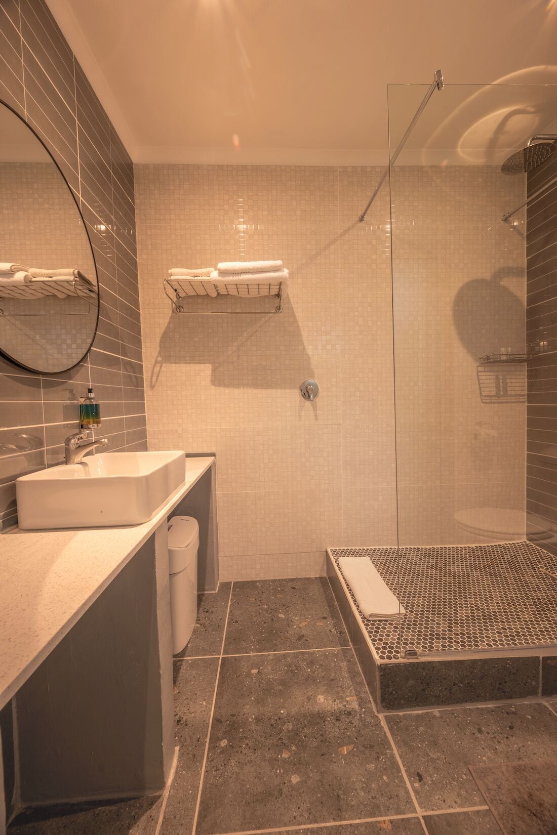 A modern bathroom with a shower, a sink, and a toilet.