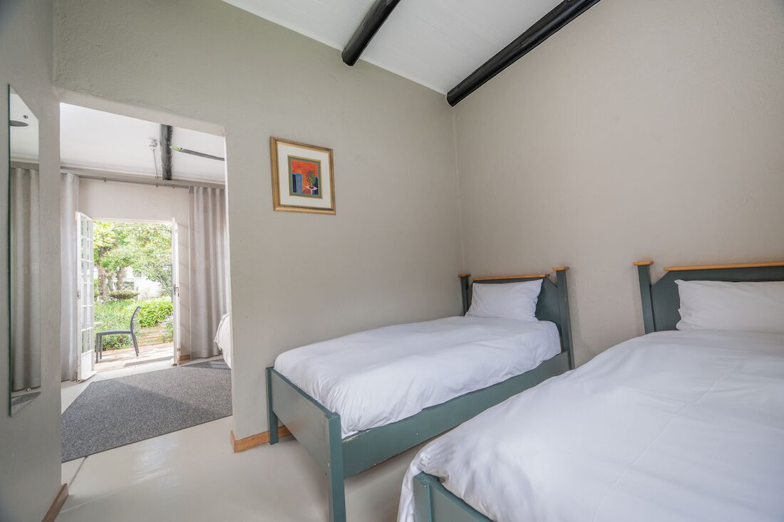 A room with two beds, a door leading outside, and a framed picture on the wall.