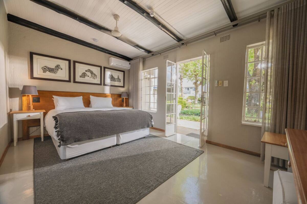 A bedroom with a bed, bedside tables, a window, and framed artwork on the wall.
