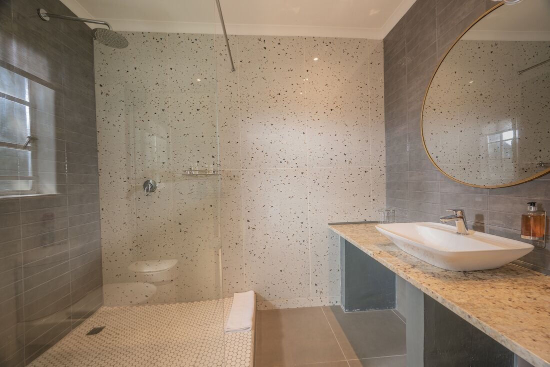 A modern bathroom with a glass-enclosed shower, a freestanding sink, and a large mirror.