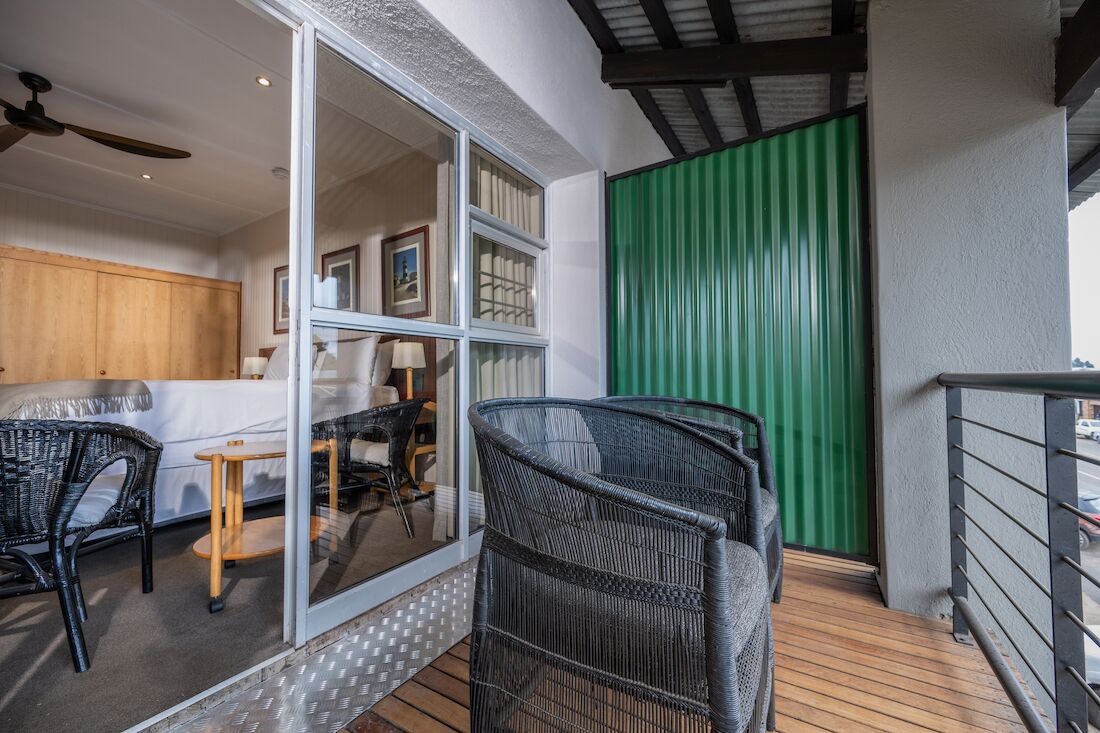 A modern interior with a glass door leading to a balcony, wicker furniture, and a green curtain.