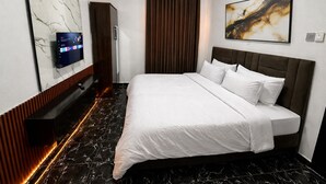 Habitación de hotel con cama, televisión, un cuadro y suelo de mármol.
