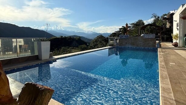 A clear view of a swimming pool with a mountain backdrop. - Private Farm - Hot Pool, Jacuzzi & Games (Sopetrán)