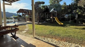 A covered outdoor area with a playground, a slide, and a bench. - Private Farm - Hot Pool, Jacuzzi & Games (Sopetrán)
