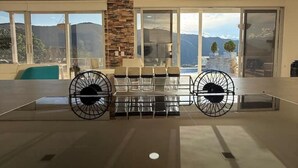 A spacious room with a large window, a stone pillar, and a seating area with chairs and a table. - Private Farm - Hot Pool, Jacuzzi & Games (Sopetrán)