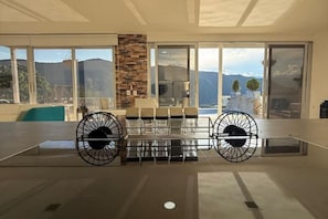 Una habitación amplia con un gran ventanal, un pilar de piedra y una zona de estar con sillas y una mesa.