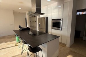 A modern kitchen with a central island, stainless steel appliances, and a clean, minimalist design.