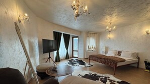 Una habitación con cama, televisión sobre un mueble bajo, candelabro y alfombra de cuero de vaca.