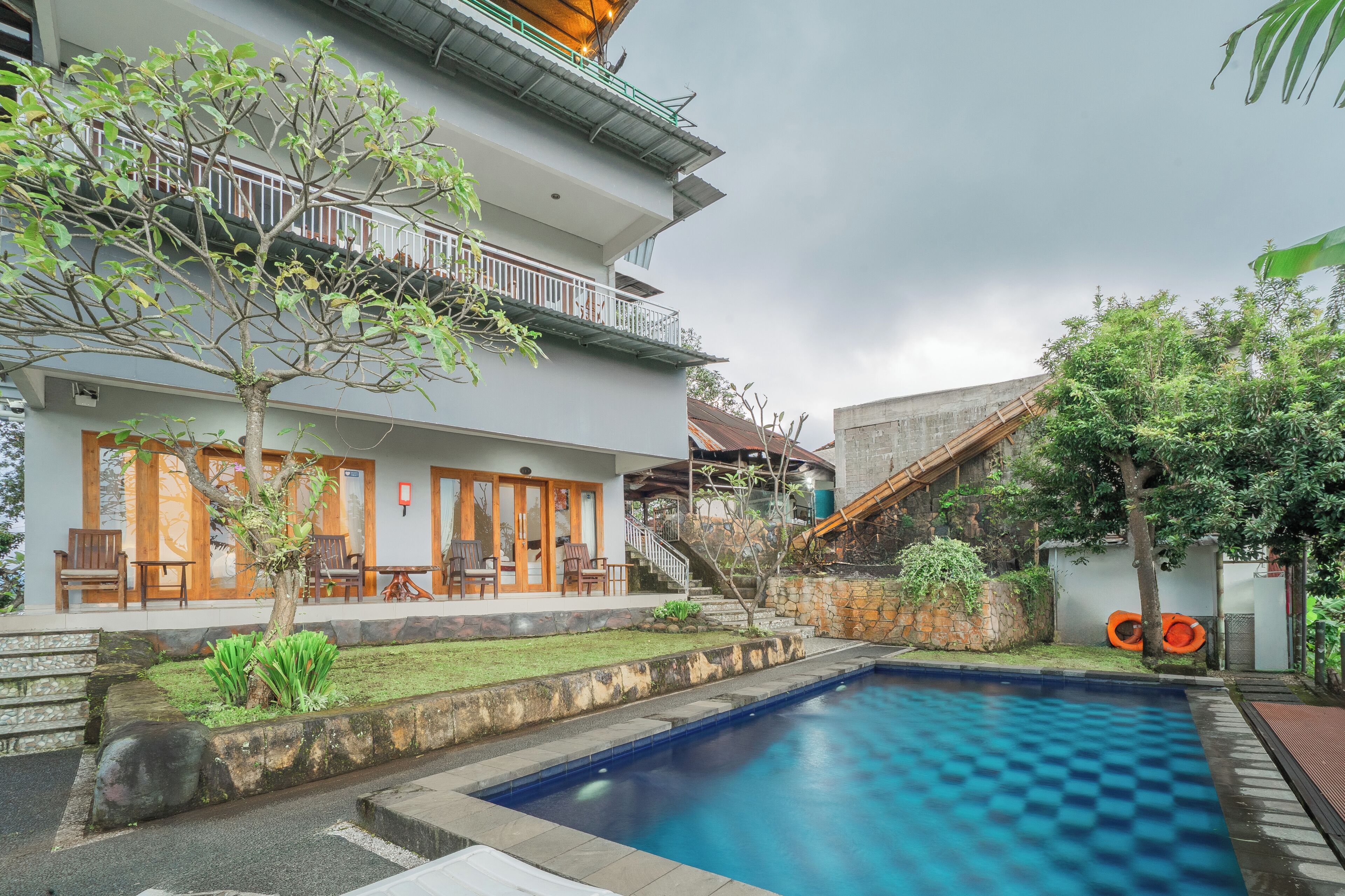 A poolside area with a pool, a staircase, and a building with a balcony.