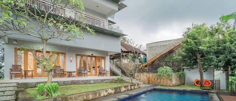 A poolside area with a pool, a staircase, and a building with a balcony.
