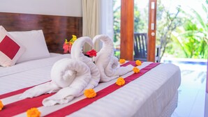 A bed with white linens, red accents, and two swan-shaped towels. - DWM Mandhasativa Homestay By Reccoma (Sawan)