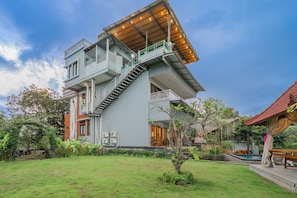 Ein modernes, zweistöckiges Haus mit großzügigem Balkon, Schwimmbad und gepflegtem Garten.