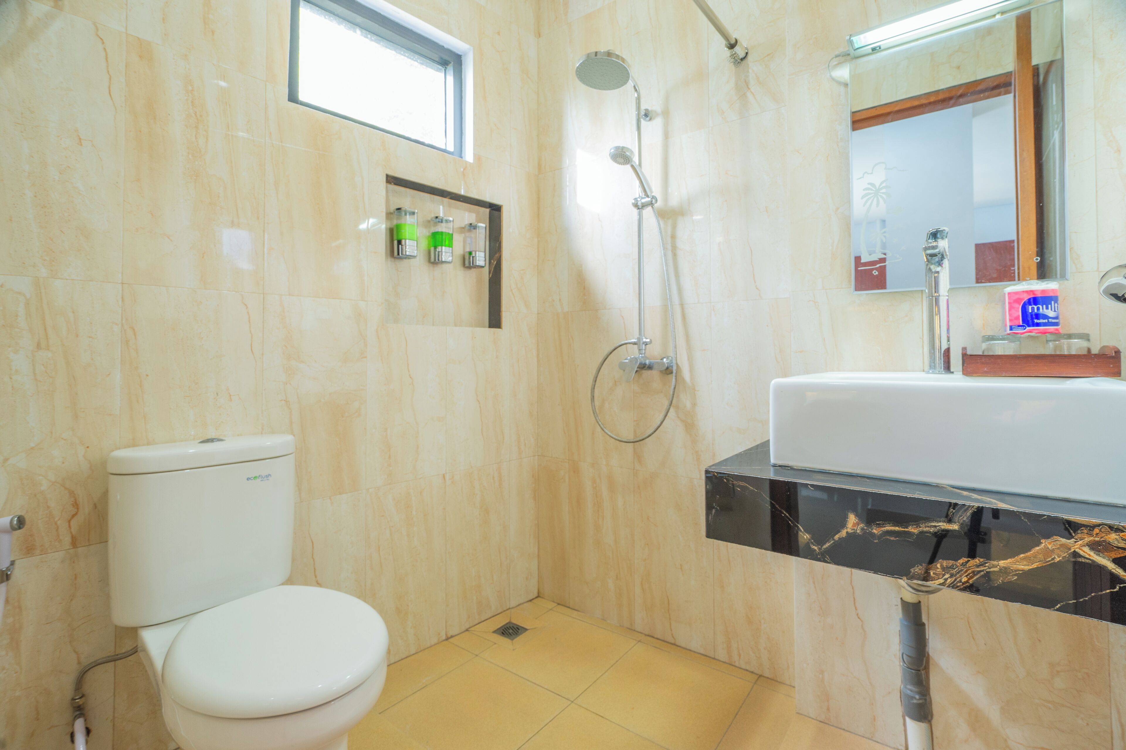 Une salle de bain comprenant des toilettes, une douche, un lavabo et un miroir.