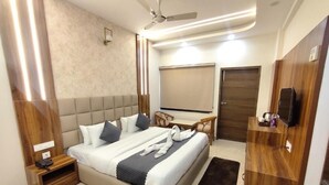 A modern hotel room with a large bed, bedside table, a flat-screen TV, a ceiling fan, and a wooden wardrobe. - hotel PS Residency (Dehradun)