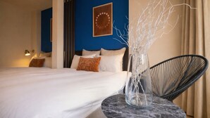 A hotel room with a bed, a round marble table, a modern chair, a decorative vase, and a wall with a circular design. - KISEN KOBE EKIMAE (Kobe)