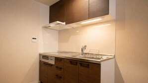 A compact kitchen with a built-in dishwasher, a stainless steel sink, and a wooden cabinet. - KISEN KOBE EKIMAE (Kobe)